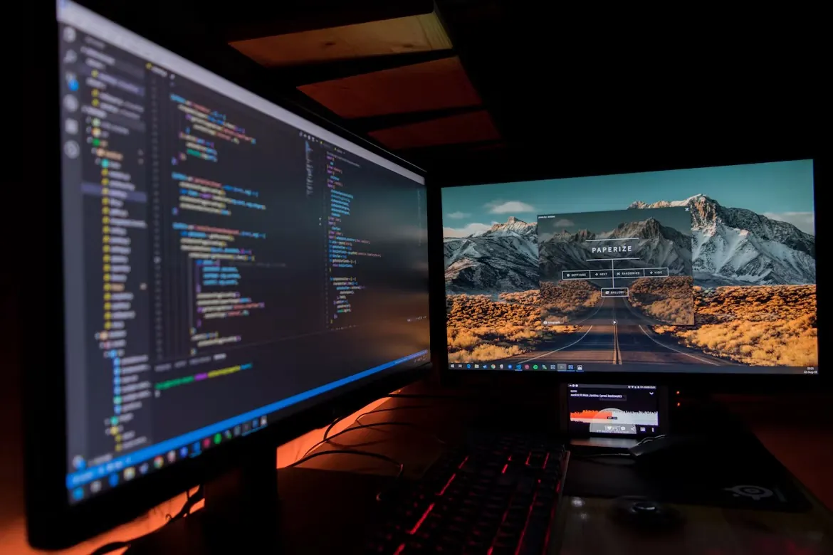 Two monitors at a desk, one showing code